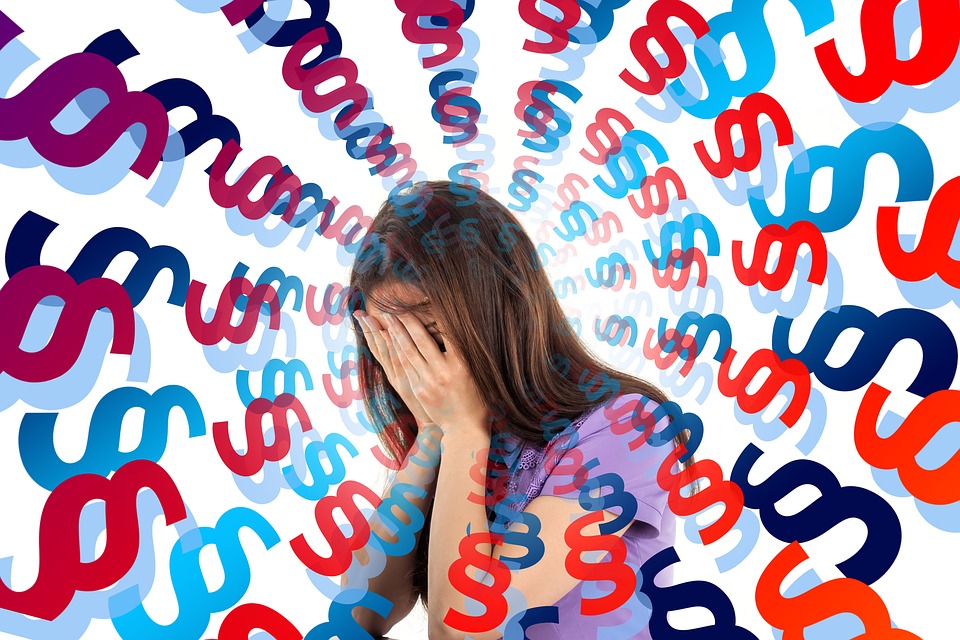 This image shows a young woman holding her head in her hands. She is experiencing sensory overload